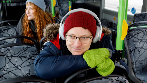 Mies kuulokkeet korvilla linja-autossa. Kuva Hanna-Kaisa Hämäläinen